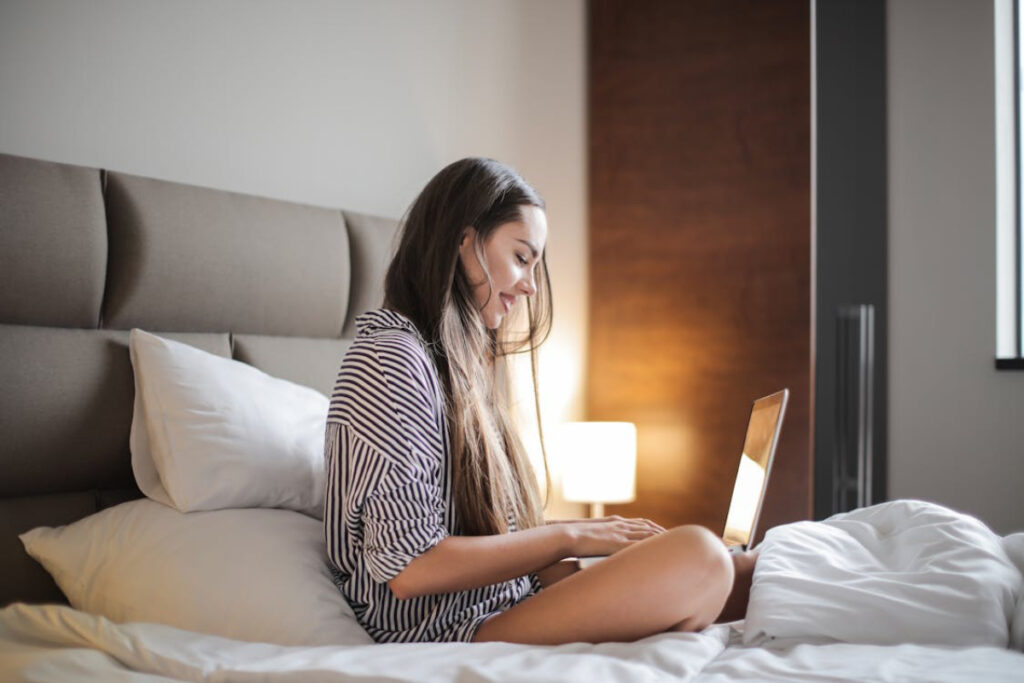 A person sits on a bed in a cozy room.