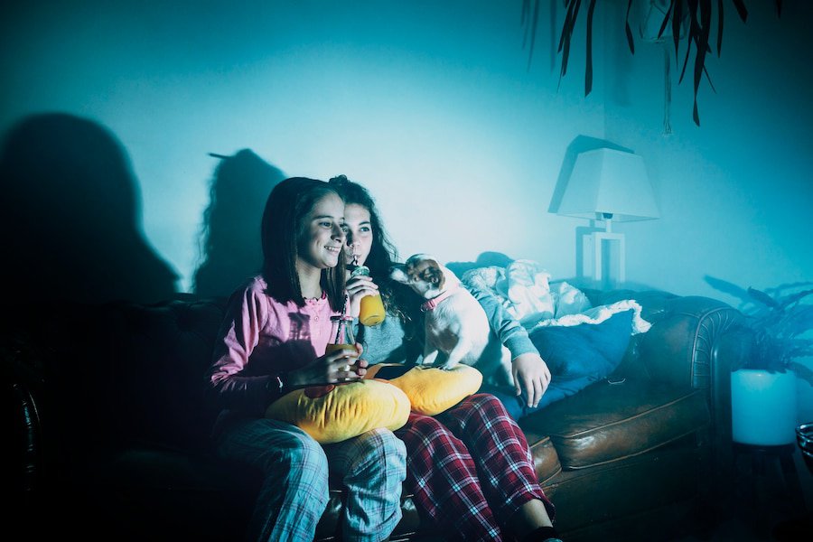 A person in cozy pajamas sits on a couch.