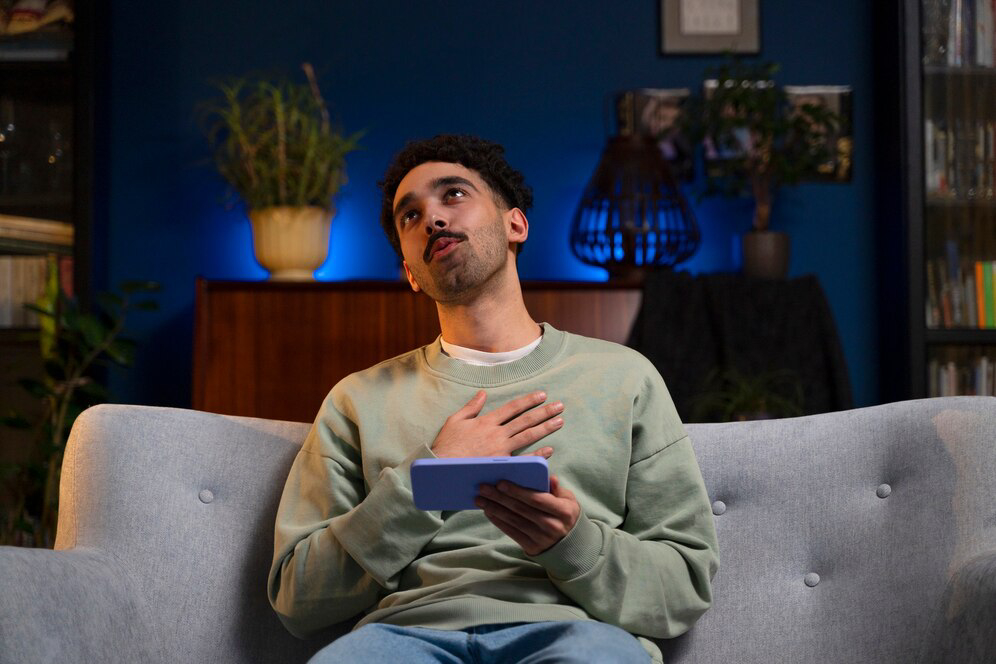 A person in a green sweater sits on a sofa.