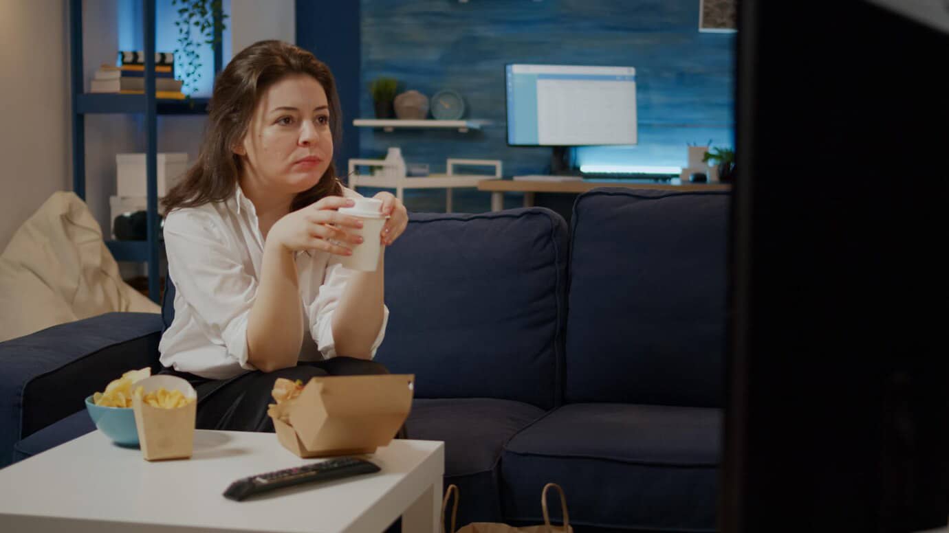A person sitting on a couch holds a drink.
