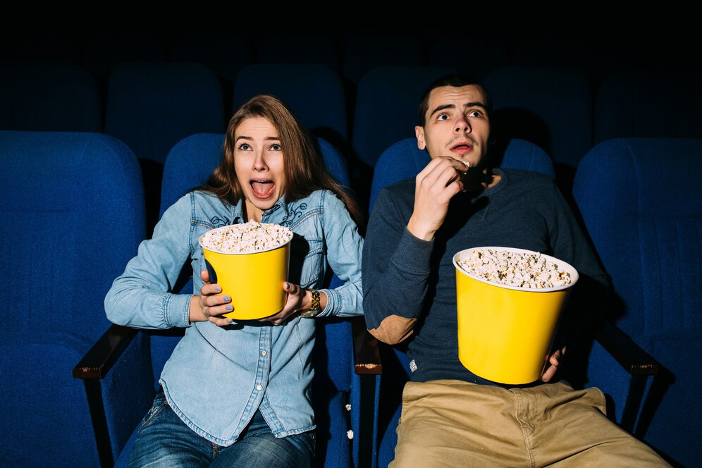 A couple in a dark movie theater.