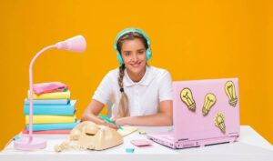 A student in a white shirt sits at a desk with a pink lamp.