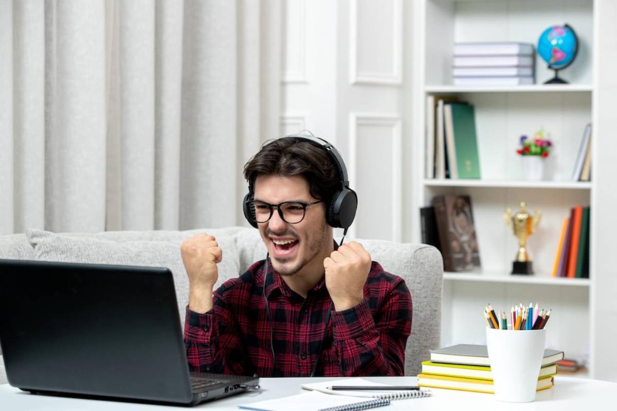 A person wearing headphones sits at a desk with a laptop.