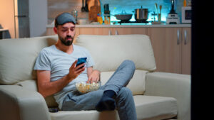 A person sits on a couch in casual attire.