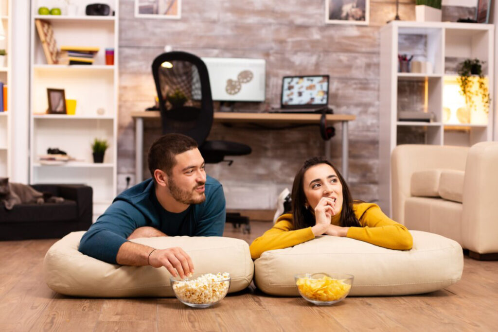 A cozy living room scene with two people lounging on large cushions.