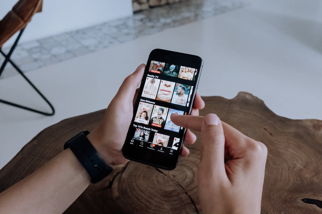 A person using a smartphone to browse Netflix.