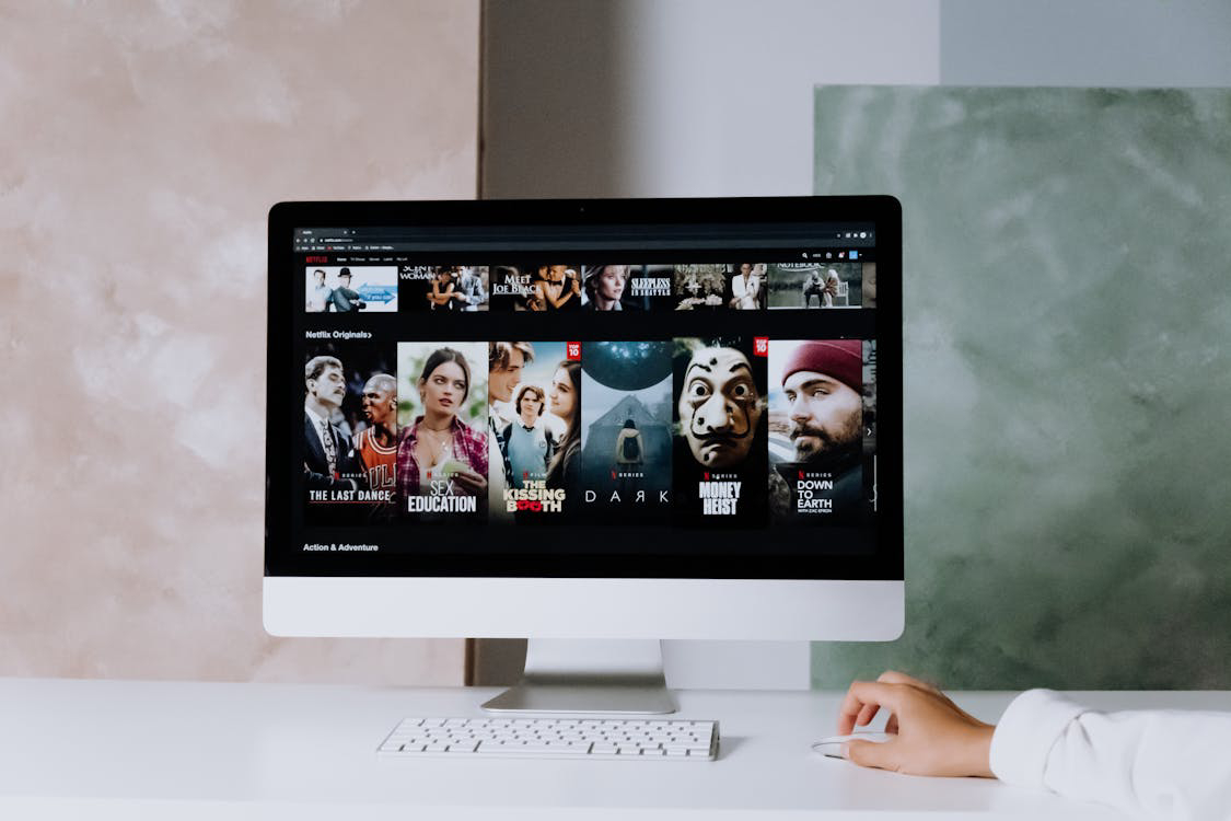 A person is browsing Netflix on a computer screen displaying various Netflix Original shows and movies.