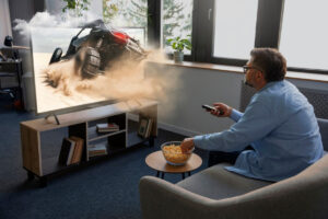 A person sitting on a couch watches an action scene on TV.