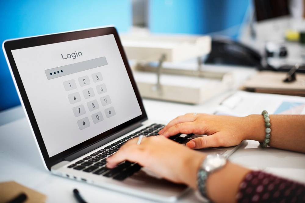 Person typing on a laptop displaying a numeric keypad login screen.