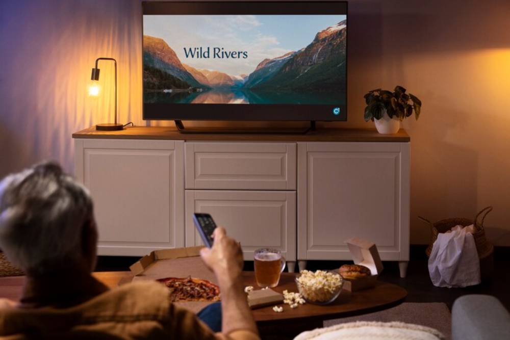 A man relaxes on a couch, watching 